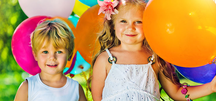 two smiling children holding balloons