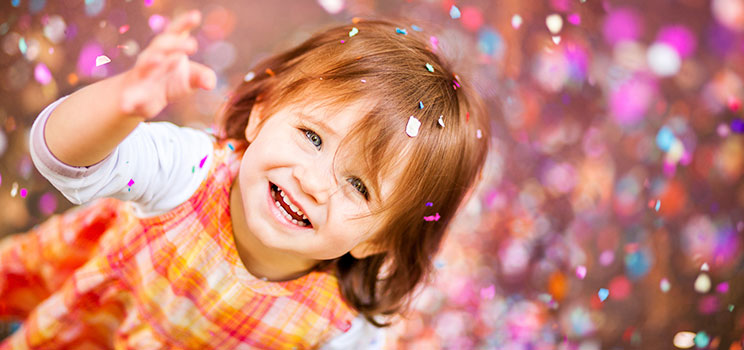 a little girl smiles as confetti rains down