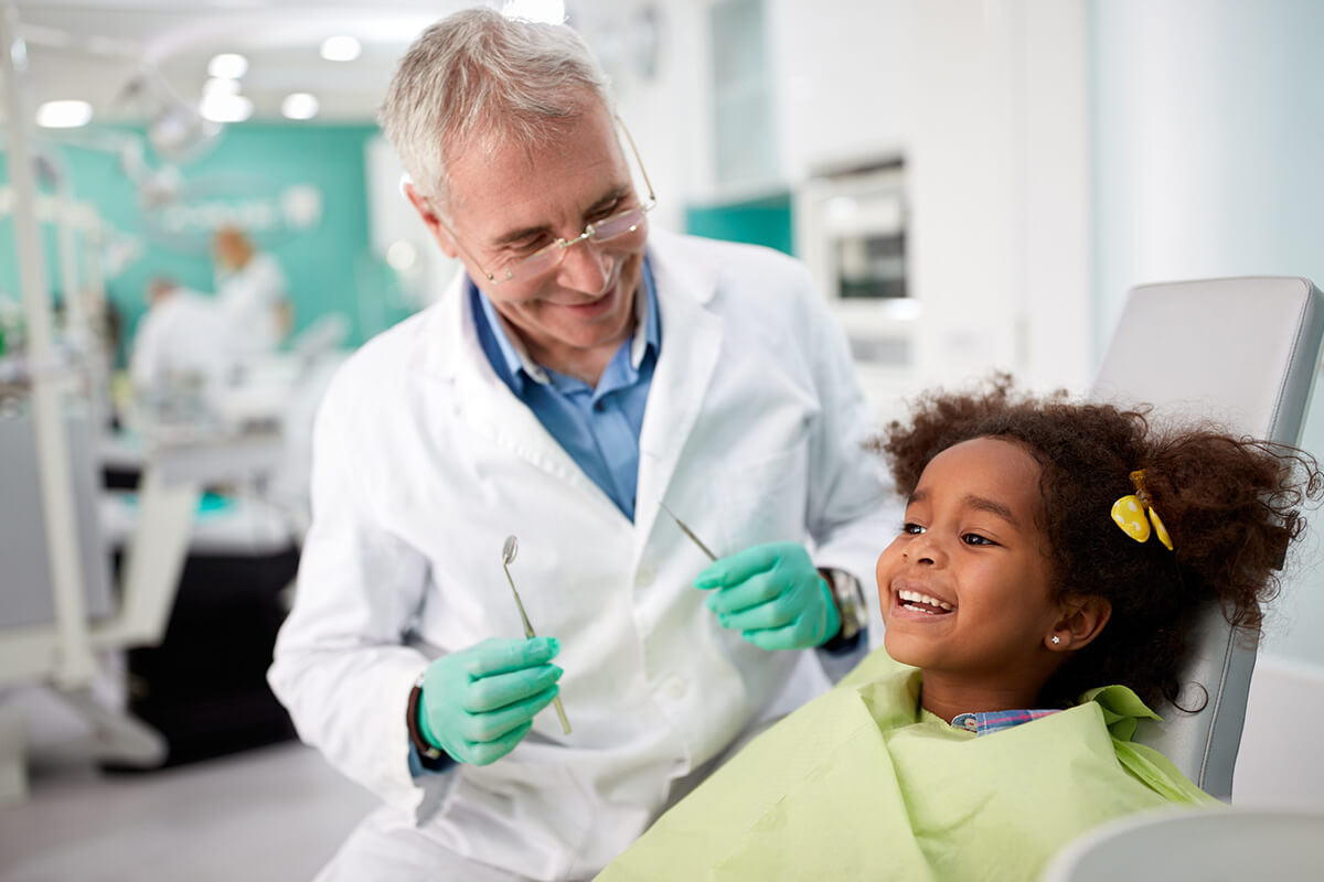 dentist and girl in a dental chair smiling